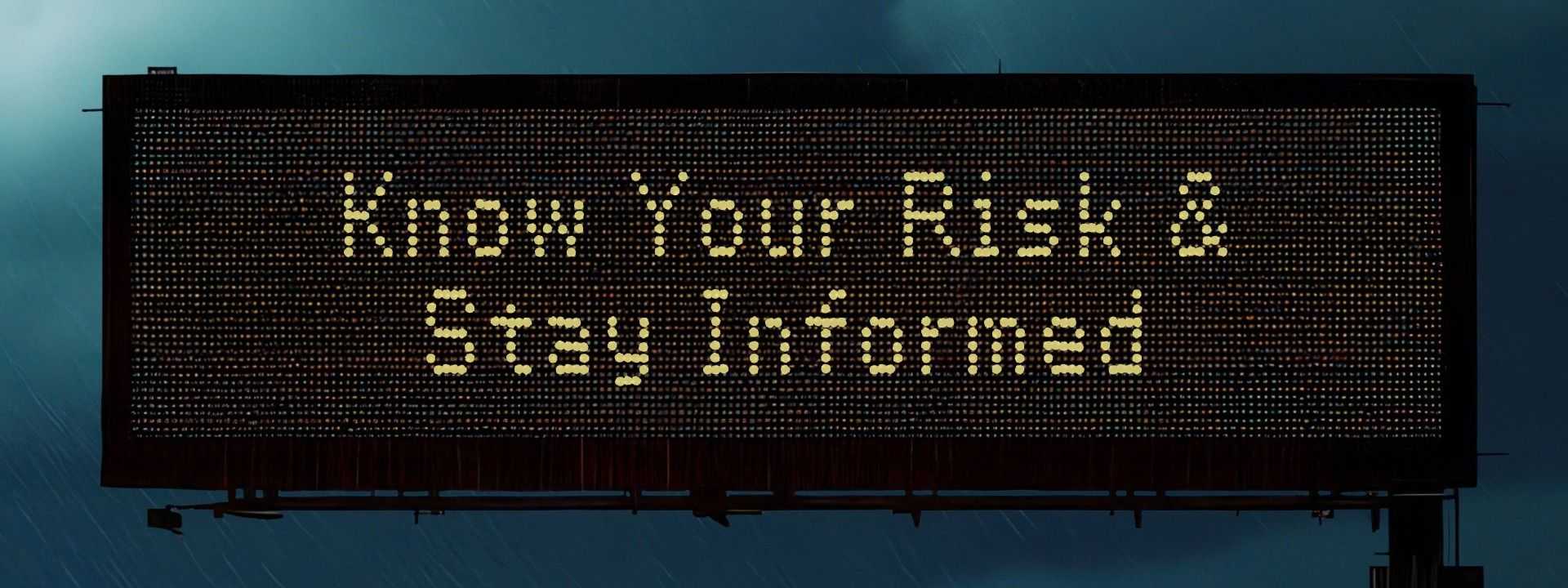 Electronic highway sign in rainy conditions reads “Know Your Risk & Stay Informed,” with blurred traffic and lights below in a stormy scene.