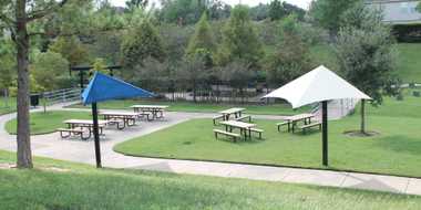 Park rest area which contains picnic tables and sun shades.