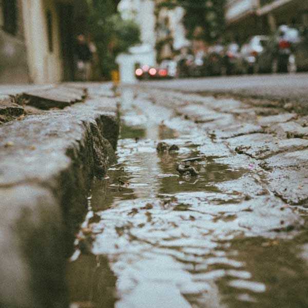 A parking lot in a city with water standing near a curb